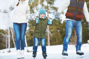 Happy little boy ice-skating with his parents together